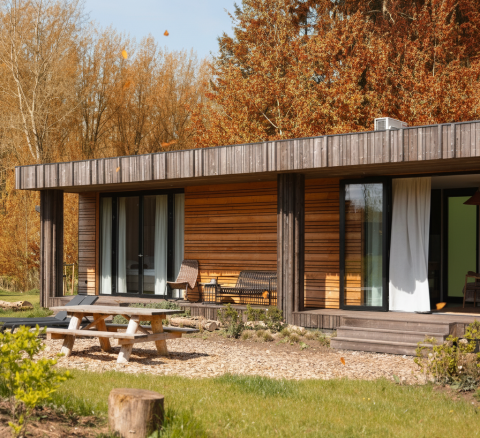 Vue extérieure de la Lodge Hottub au Resort de Parel, Pays-Bas, cabane en bois entourée d’arbres d’automne.