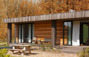 Buitenaanzicht van Lodge Hottub bij Resort de Parel in Nederland, moderne houten lodge tussen herfstbomen.
