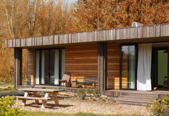 Vue extérieure de la Lodge Hottub au Resort de Parel, Pays-Bas, cabane en bois entourée d’arbres d’automne.