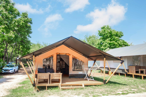 Safaritent Comfort + airco, moderne safaritent met terras, zithoek en uitzicht op bomen en lucht.