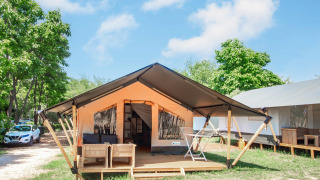 Safaritent Comfort + airco, modern safari tent with deck, outdoor seating and view of trees and sky.