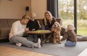 Familia se divierte jugando a un juego de mesa y con su perro en Holiday villa Amalia 6, Hofparken De Bergvennen.