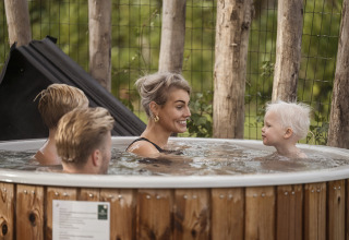 Family enjoying a hot tub outside Vacation villa Amalia 4 at Hofparken De Bergvennen in the Netherlands.