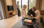 Familia disfruta armando un rompecabezas en la sala de Vacation Villa Amalia 4 con jacuzzi en Hofparken De Bergvennen.
