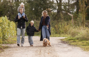 Familia paseando con perro por el sendero de Vacation villa Amalia 4 con sauna y jacuzzi en Hofparken De Bergvennen.