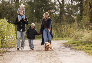 Familie går tur med hund på sti ved Vacation villa Amalia 4 med sauna og spabad i Hofparken De Bergvennen.