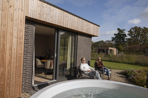 Mensen relaxen bij Vacation villa Amalia 2 met sauna en hot tub, modern vakantiehuis in het groen.
