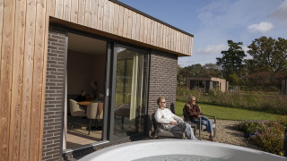 Zwei Personen entspannen sich vor der Vacation villa Amalia 2 mit Sauna und Whirlpool im Grünen.