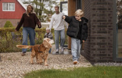 Familia con perro llegando a Vakantievilla Amalia 4 con sauna y jacuzzi en Hofparken De Bergvennen, Países Bajos.