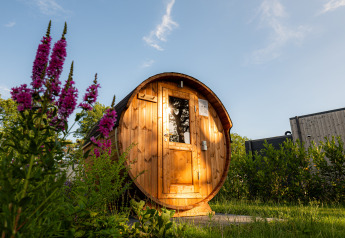 Houten saunaton aan Holiday villa Amalia 2, omringd door bloemen en groen in Hofparken Wiltershaar.