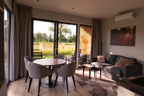 Salon moderne de la villa Amalia 2 avec coin repas et vue sur la nature, Hofparken Wiltershaar aux Pays-Bas.