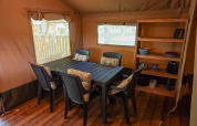 Innenansicht eines Safarizeltes mit Esstisch, Stühlen und Regal auf Camping De Rammelbeek, Niederlande.