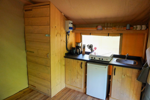 Køkkenområde i en safaritelt på Camping De Rammelbeek med træskabe, komfur og håndvask.