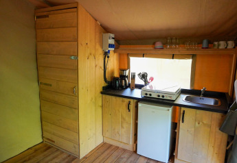 Angolo cucina in una tenda safari al Camping De Rammelbeek con mobili in legno e piano cottura.
