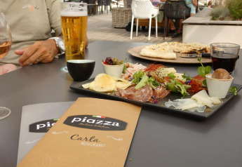 Pasto all'aperto al glamping con antipasti italiani, bevande e menù sul tavolo in ambiente rilassato.