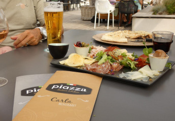 Repas en plein air lors d’un séjour glamping avec antipasti italiens, boissons et menus sur la table.