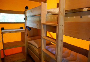 Indvendigt billede af en safaritelt med køjesenge og træreoler på Camping De Rammelbeek i Holland.