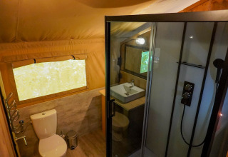 Badeværelse i safaritelt med toilet, håndvask og brusekabine ved søen på Camping De Rammelbeek.