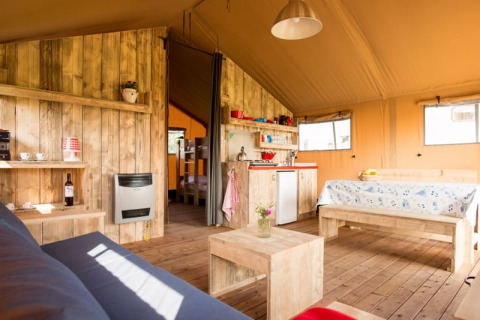 Intérieur d'une tente safari de luxe, Luxe Ranchtent, avec des meubles en bois et ambiance chaleureuse.