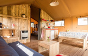 Interior de una tienda safari de lujo, Luxe Ranchtent, con muebles de madera y ambiente acogedor.