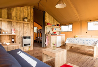 Intérieur d'une tente safari de luxe, Luxe Ranchtent, avec des meubles en bois et ambiance chaleureuse.