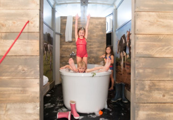Bambini che giocano nella vasca da bagno nella tenda safari Luxe Ranchtent, con pareti in legno e mucche.