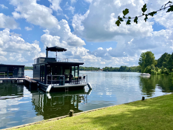 Hausboot mit Dachterrasse und Whirlpool am Marina Mookerplas in den Niederlanden an einem sonnigen Tag.