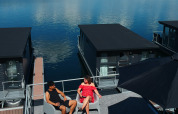 Ein Paar entspannt auf dem Dach einer Hausboot-Lodge an der Marina Mookerplas, Niederlande, bei Sonnenschein.