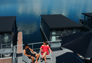 A couple relaxes on a roof terrace of a houseboat lodge at Marina Mookerplas in the Netherlands on a sunny day.