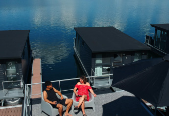 Ein Paar entspannt auf dem Dach einer Hausboot-Lodge an der Marina Mookerplas, Niederlande, bei Sonnenschein.