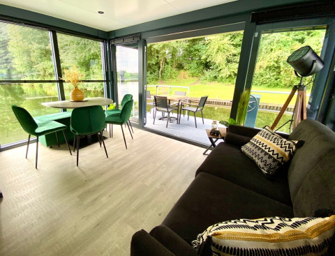 Moderne leefruimte en eethoek in Houseboat Marina Mookerplas met zicht op het water en terras.