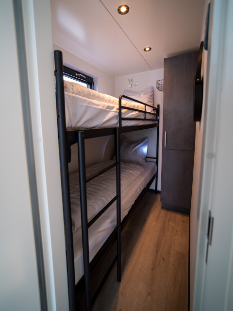 Smalle slaapkamer met een modern stapelbed op Houseboat Marina Mookerplas in Nederland.