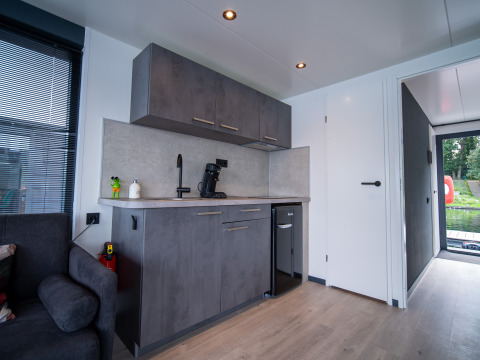 Modern kitchenette in a lodge at Houseboat Marina Mookerplas, Netherlands, featuring grey cabinets and minibar.