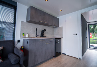 Moderne keukenhoek in een lodge van Houseboat Marina Mookerplas in Nederland met grijze kasten en minibar.
