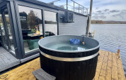 Jacuzzi exterior en una terraza de madera junto a una casa flotante moderna en Marina Mookerplas, Países Bajos.