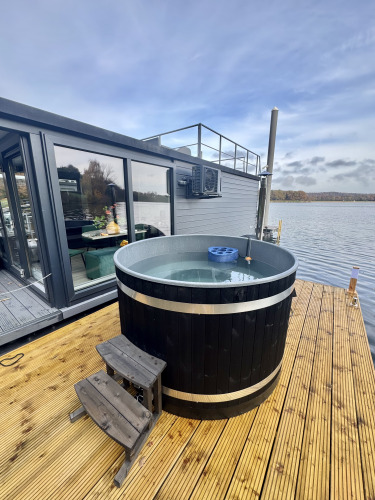 Whirlpool auf der Terrasse eines modernen Hausboots bei der Marina Mookerplas in den Niederlanden am Wasser.