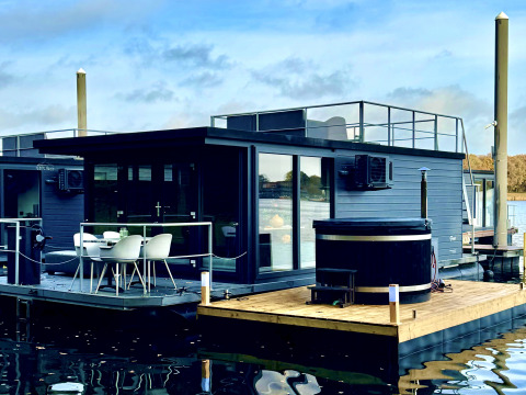 Moderne woonboot in Marina Mookerplas met dakterras en hottub, op het water met rustige sfeer.