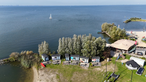 Luchtfoto van tiny wagons aan het water bij Marina Parcs Almere, Nederland, omgeven door bomen en water.