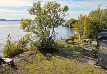 Vista dal Tiny Wagon al Marina Parcs Almere nei Paesi Bassi con lago, alberi e tavoli da picnic.