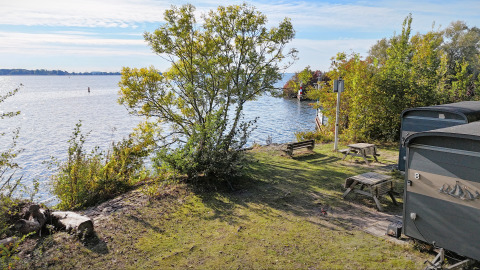 Vista dal Tiny Wagon al Marina Parcs Almere nei Paesi Bassi con lago, alberi e tavoli da picnic.