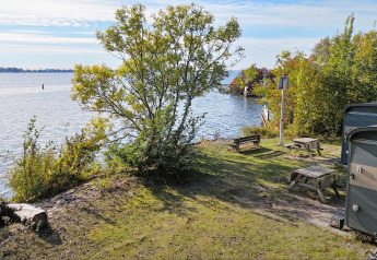 Blick vom Tiny Wagon bei Marina Parcs Almere in den Niederlanden auf See, Picknicktische und Natur.
