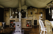 Interior view of a rustic safari tent with wooden furnishings and wood stove at Feather Down De Oude Melkstal.