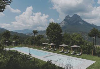 Outdoor swimming pool at Wecamp Pedraforca with mountain scenery and greenery in Catalonia, Spain.