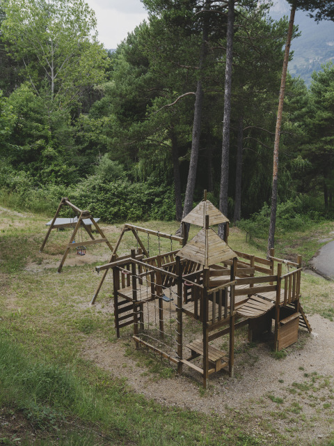 Houten speeltoestel tussen bomen bij Wecamp Pedraforca vakantiepark in Catalonië, Spanje.