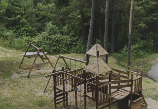 Houten speeltoestel tussen bomen bij Wecamp Pedraforca vakantiepark in Catalonië, Spanje.