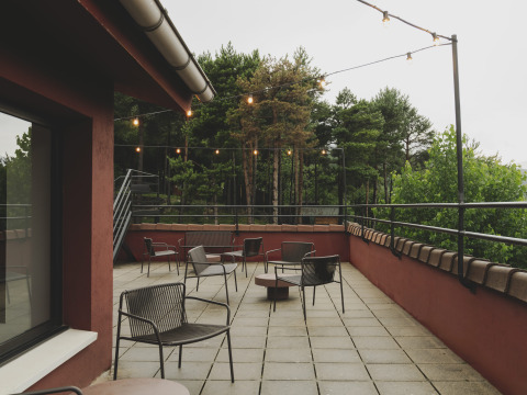 Buitenterras met stoelen en lichtslingers bij Wecamp Pedraforca vakantiepark, omringd door bomen.