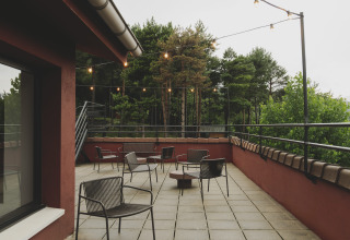 Buitenterras met stoelen en lichtslingers bij Wecamp Pedraforca vakantiepark, omringd door bomen.