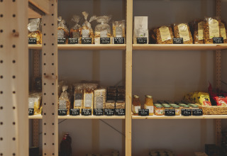 Estanterías de madera con cestas, snacks y tarros de miel en una tienda en Wecamp Pedraforca, Cataluña.