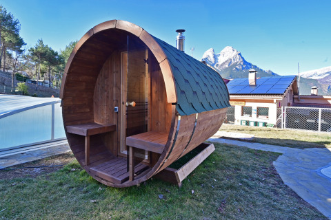 Houten ton-sauna bij Wecamp Pedraforca vakantiepark in Catalonië, Spanje, met bergen op de achtergrond.