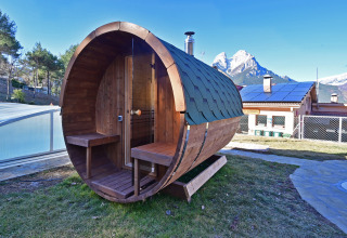 Houten ton-sauna bij Wecamp Pedraforca vakantiepark in Catalonië, Spanje, met bergen op de achtergrond.